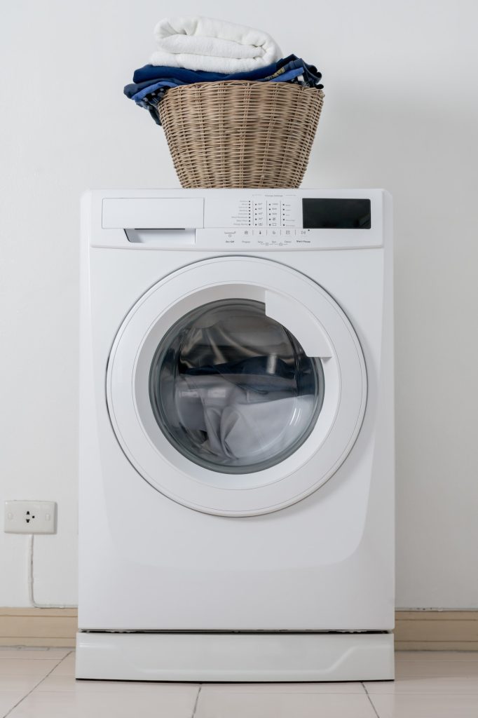 Close up washing machine and clothes in basket on white background. Laundry concept.