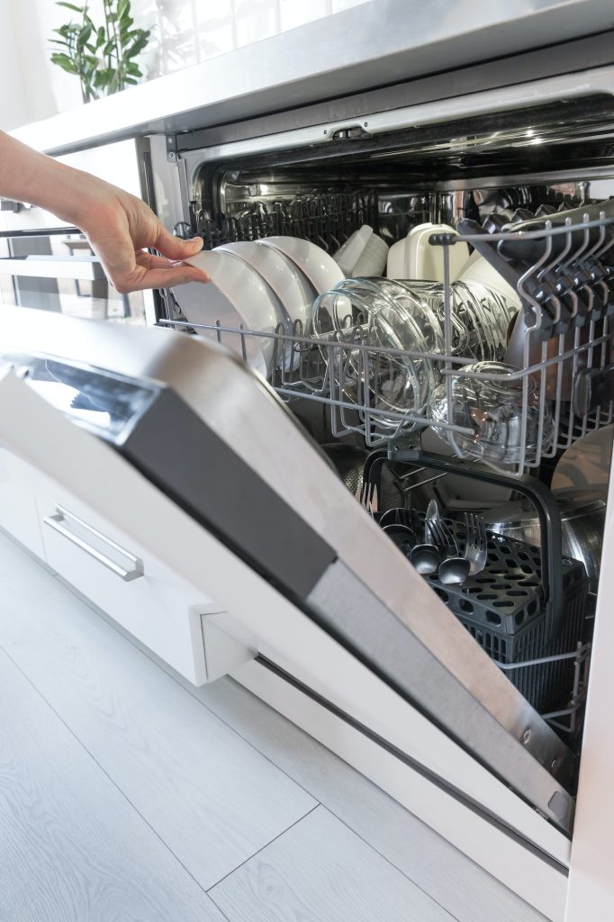 Man hand holding clean dishes after washing in the dishwasher.